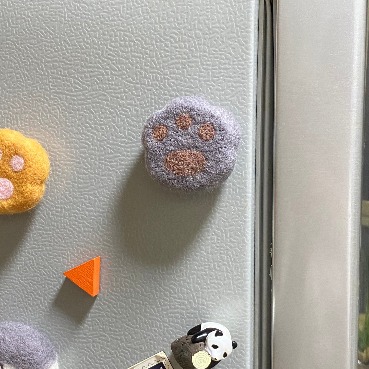 Handmade wool felt fridge magnet shaped like an British Shorthair Blue cat paw, adding a cozy, personal touch for cat lovers