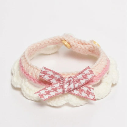 Handmade pink crochet cat collar made from soft yarn, featuring a decorative ribbon.