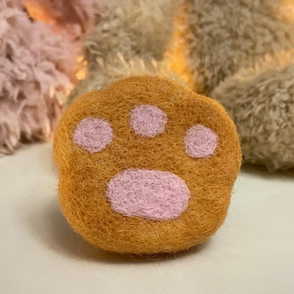 Handmade wool felt fridge magnet shaped like an orange tabby cat paw, adding a cozy, personal touch for cat lovers.