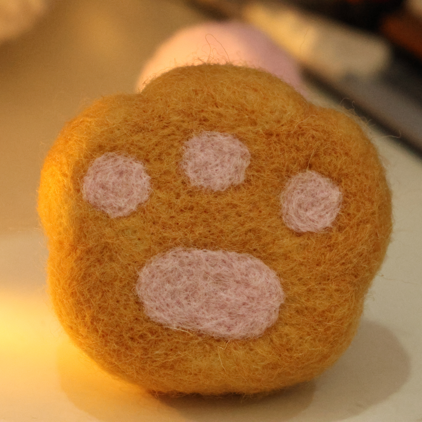 Handmade wool felt fridge magnet shaped like an orange tabby cat paw, adding a cozy, personal touch for cat lovers